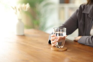 Woman hand holding water glass on wooden table