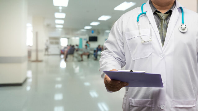 Doctor in gown uniform with patient chart standing on patient screening point OPD background.