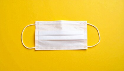 A white disposable face mask lies flat against a bright yellow background—evoking containment, vulnerability, and the quiet choreography of protection, silence, and systemic tension.