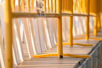 A low angle close up of yellow barriers and white chairs for an event.