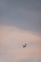 A plane is flying in the sky with a cloudy background