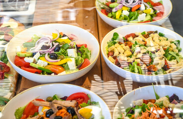 Fresh salad in bowls at the restaurant. Chopped vegetables in a bowl. Tomato, onion, cheese, arugula, olives.