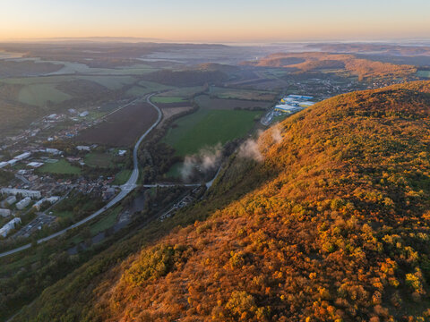 Aerial view of golden sunlight kissing the rugged hills, a serene valley unfolding below, and the town nestled peacefully, Ple&Aring;&iexcl;ivec, Ko&Aring;&iexcl;ice Region, Slovakia.