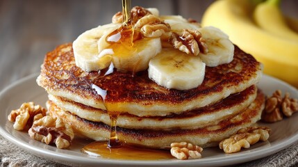 Stack of pancakes topped with banana slices, walnuts, and maple syrup (1)