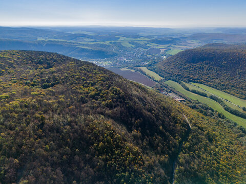 Aerial view of the vibrant green forests meeting the village nestled in the valley, a tapestry of nature and civilization, Ple&Aring;&iexcl;ivec, Ko&Aring;&iexcl;ice Region, Slovakia.