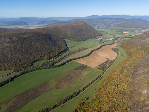 Aerial view of autumn's touch paints the landscape with gold and green hues, a valley unfolds between forested hills, Ple&Aring;&iexcl;ivec, Ko&Aring;&iexcl;ice Region, Slovakia.
