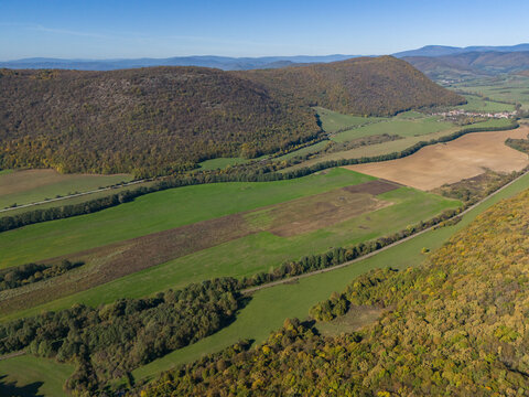Aerial view of rolling hills cloaked in the warm hues of autumn foliage meeting the emerald fields below, Ple&Aring;&iexcl;ivec, Ko&Aring;&iexcl;ice Region, Slovakia.