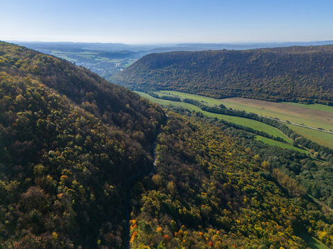 Aerial view of a sun-drenched valley nestled between rolling hills, a tapestry of greens and golds, with the town of Ple&Aring;&iexcl;ivec in the distance, Ple&Aring;&iexcl;ivec, Ko&Aring;&iexcl;ice Region, Slovakia.
