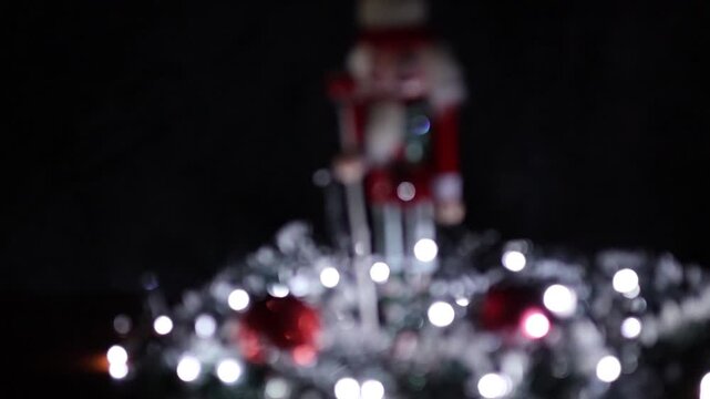 Una toma desenfocada  de un soldadito de juguete o cascanueces de navidad rodeado de bolas de navidad y luces de color blancas. Decoraci&oacute;n de navidad y fin de a&ntilde;o