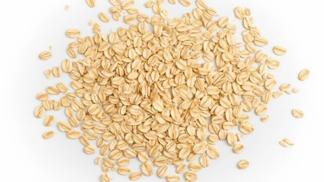 Golden oats falling gracefully on white surface in slow motion
