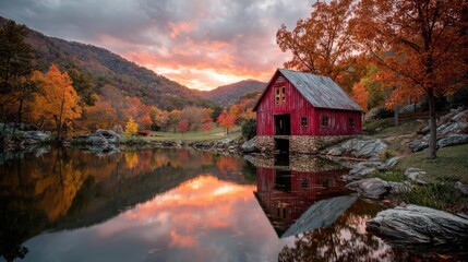 Red barn reflected in calm autumn lake at sunset