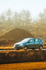 Obraz premium Compact hatchback driving on country road