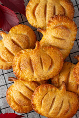 Pumpkin mini pies or hand pies with glass of coffee on a stone background. Traditional autumn dessert for Halloween and Thanksgiving. Copy space