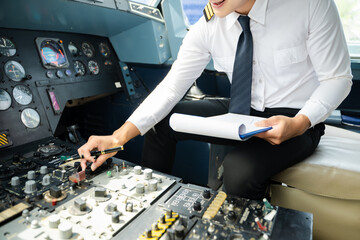 Professional airline pilot in uniform inspecting cockpit control panels during safety checks, ideal for aviation, travel, and airline safety themes.