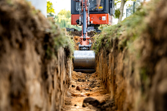 Mini excavator bucket in a trench at a construction site