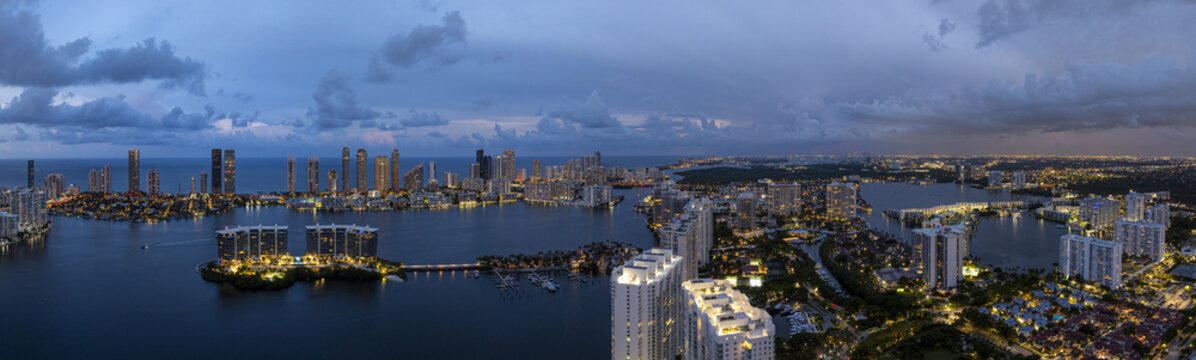 Aerial view of the illuminated coastal Sunny Isles Skyline and intracoastal waterways reflecting the city lights under the twilight sky, Aventura, Florida, United States.