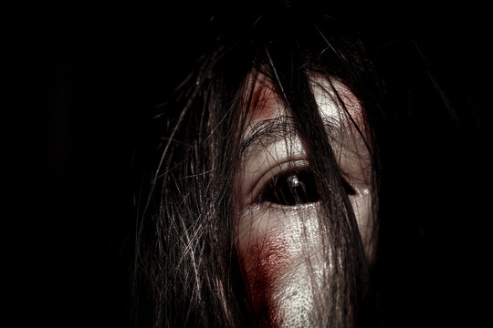 Horror Ghost Woman Portrait with Bloody Face and Dark Hair in Darkness
