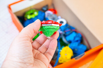 Hand holding spinning top toy, classic game and childhood fun, vibrant Beyblade spinning top toys, Engaging in indoor game with various Beyblade-style Set, Childhood play, Frankfurt