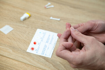 Blood typing test being performed, showing results on card, focusing on health and diagnostics, personal health and awareness, prevention self-care monitoring, blood collection, self-testing