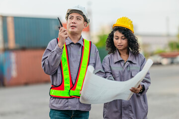 Industrial container workers discuss sustainable logistics operations. Analyzing blueprint,...