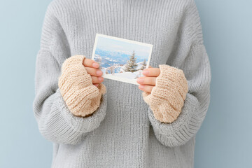 warm cozy hands in mittens gently hold christmas card featuring beautiful winter landscape