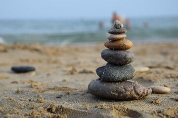 A delicate stack of smooth stones, balanced with care on the beach, framed by the gentle ocean.