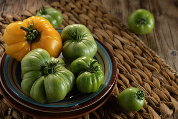 Freshly harvested heirloom tomatoes arranged on colorful ceramic plates and rustic woven mat