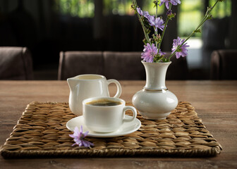 Morning coffee setup with flowers on a wooden table in a cozy cafe environment