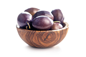 Ripe plums in bowl isolated on white background.