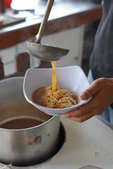 a hand is making a cheap street food spicy japanese ramen. Portrait or vertical mode, suitable for social media