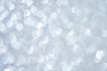 Abstract silver bokeh lights on soft gray background with circular blurred patterns.