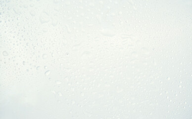 Close up of water droplets on glass surface with soft pastel background.