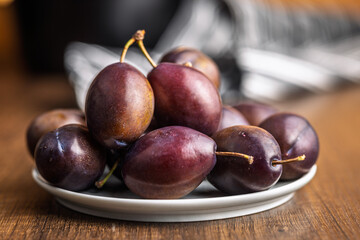 Ripe plums on plate  on wooden table.