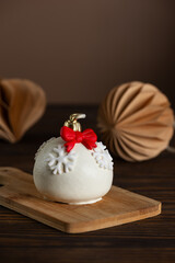 Christmas ball cakes with red bows and snowflakes and cup of coffee on a table. Vertical orientation.