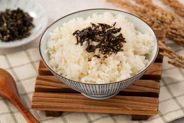 A bowl of white rice topped with seasoned seaweed and white sesame.