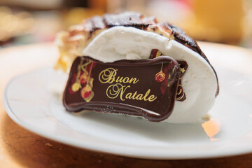 vista macro nel dettaglio di un tipico dolce natalizio, un tronchetto di natale, a base di pan di spagna, crema, panna e cioccolato