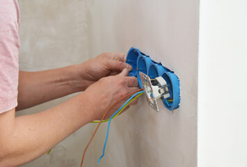 Electrician installing new electrical outlets in the wall electric boxes