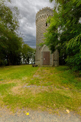 Der historische Bismarckturm erhebt sich zwischen Bäumen. Über dem massiven Natursteinbau zieht...