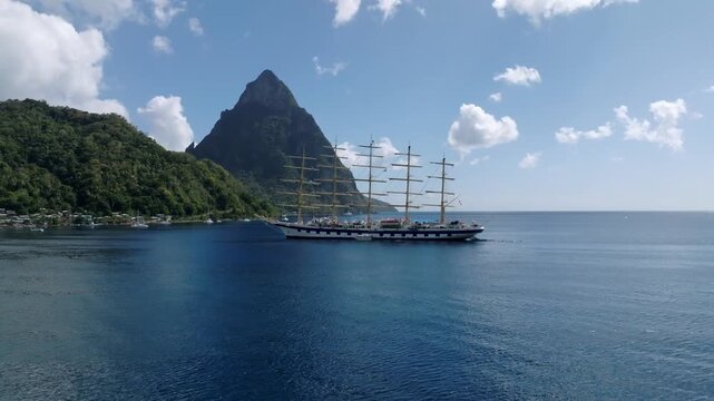 Aerial view of a majestic large ship sailing on the tranquil blue waters, juxtaposed against the dramatic backdrop of lush mountains, Le Pitons, Soufri&egrave;re, Saint Lucia.