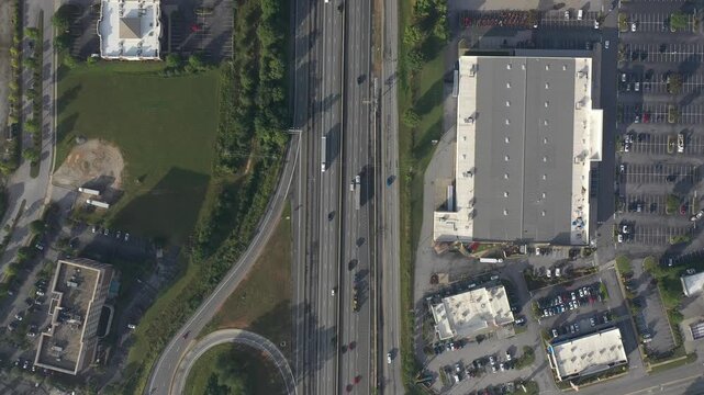 Aerial view of a bustling highway cutting through the landscape, adjacent to buildings and parking lots, a dynamic scene, Greenville, South Carolina, United States.