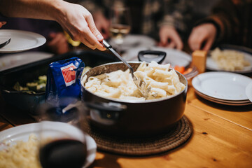 A group of friends sharing a joyful meal with a delicious pasta dish at a table.