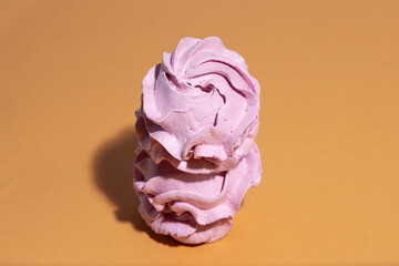 Homemade zephyr without sugar on vibrant orange background, delicate marshmallow sweets for cozy festive mood.