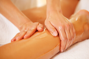 Naklejka premium Hands massaging oiled leg with smooth skin image