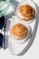 Airy shu cream puff dessert with soft filling, served on white plate, elegant light low calorie sweet for healthy lifestyle.