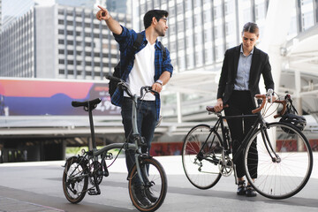 Commuting to work with bicycle. Businessman businesswoman cycling to office in downtown district....