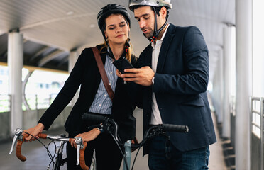 Fototapeta premium Commuting to work with bicycle. Businessman businesswoman cycling to office in downtown district. Modern diverse people use eco transportation on city street. Environmental pollution, climate change.