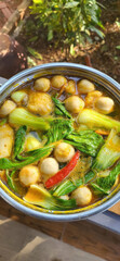 Simmering pot of verdant bok choy and golden fish balls, evoking Lunar New Year festivities and Autumn Equinox feasts