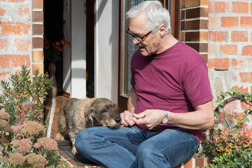 Mann mit Dackel sitzen am Hauseingang