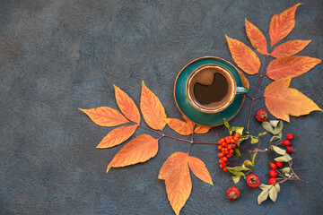 Autumn mood, a cup of coffee among autumn leaves on a wooden dark table with copy space. Top view.