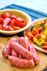 Raw Sausages, Tomatoes, Peppers, Zucchini on Cutting Board